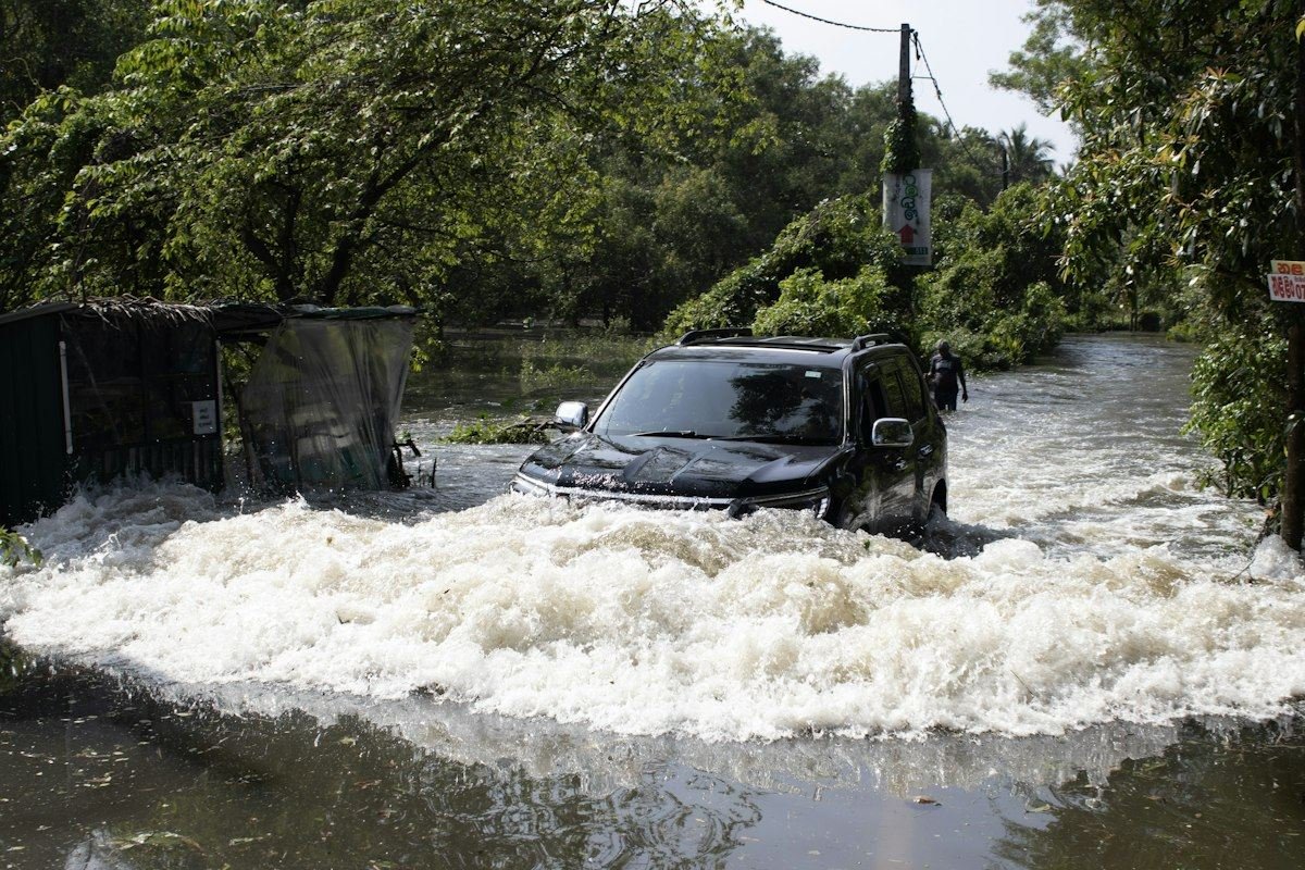 A black suv drives through a flooded street