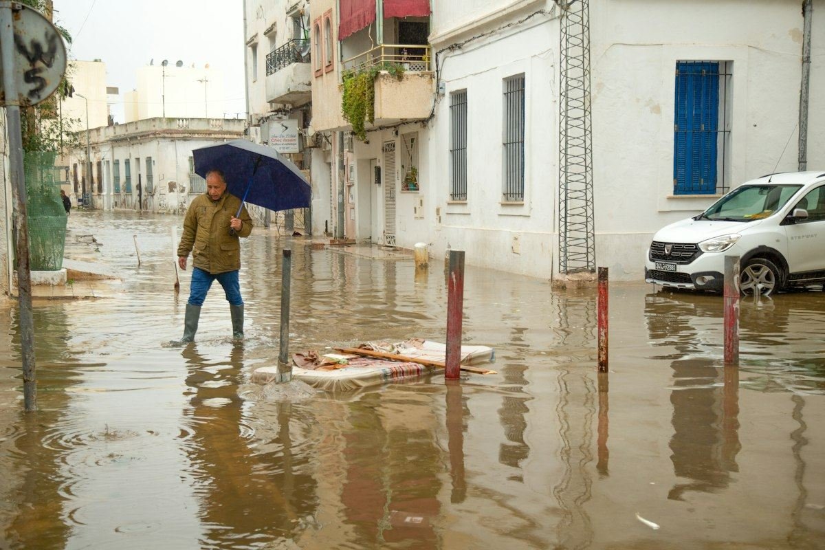 Man walks through flooded street with umbrella