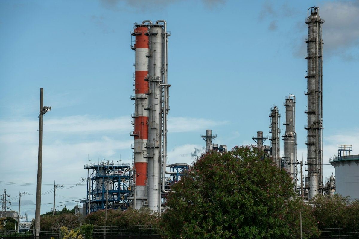 Oil refinery towers stand against a blue sky