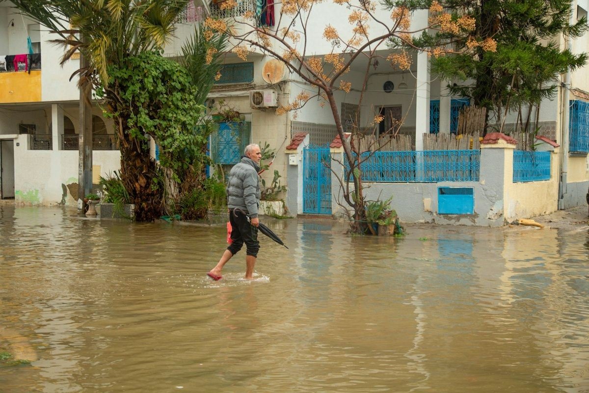 Man walks through flooded street with umbrella