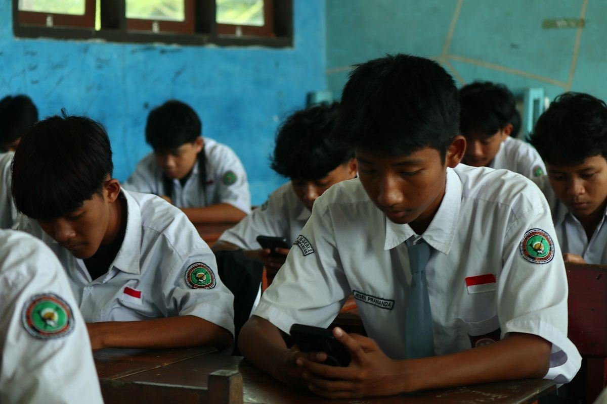 Students in uniform looking at their phones in a classroom