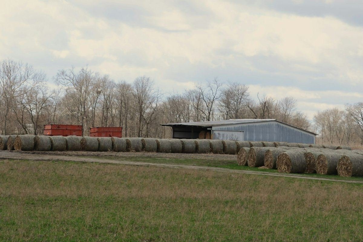 Farm field with hay bales, barns, and water tanks