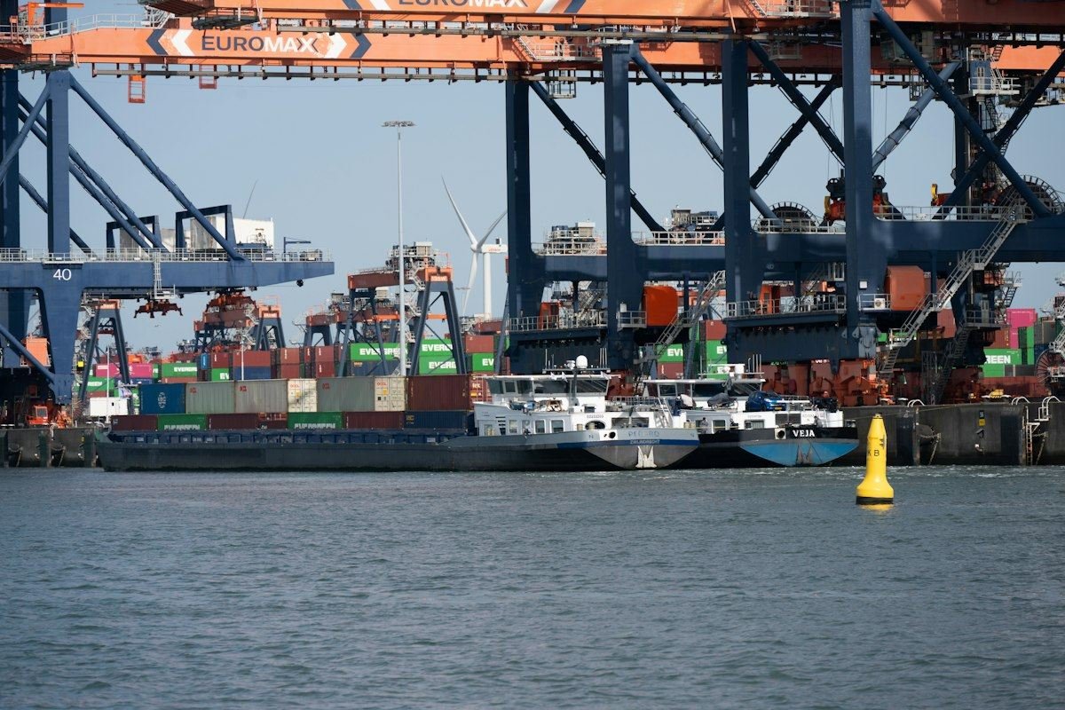 Busy port with container ships, cranes, and a yellow buoy