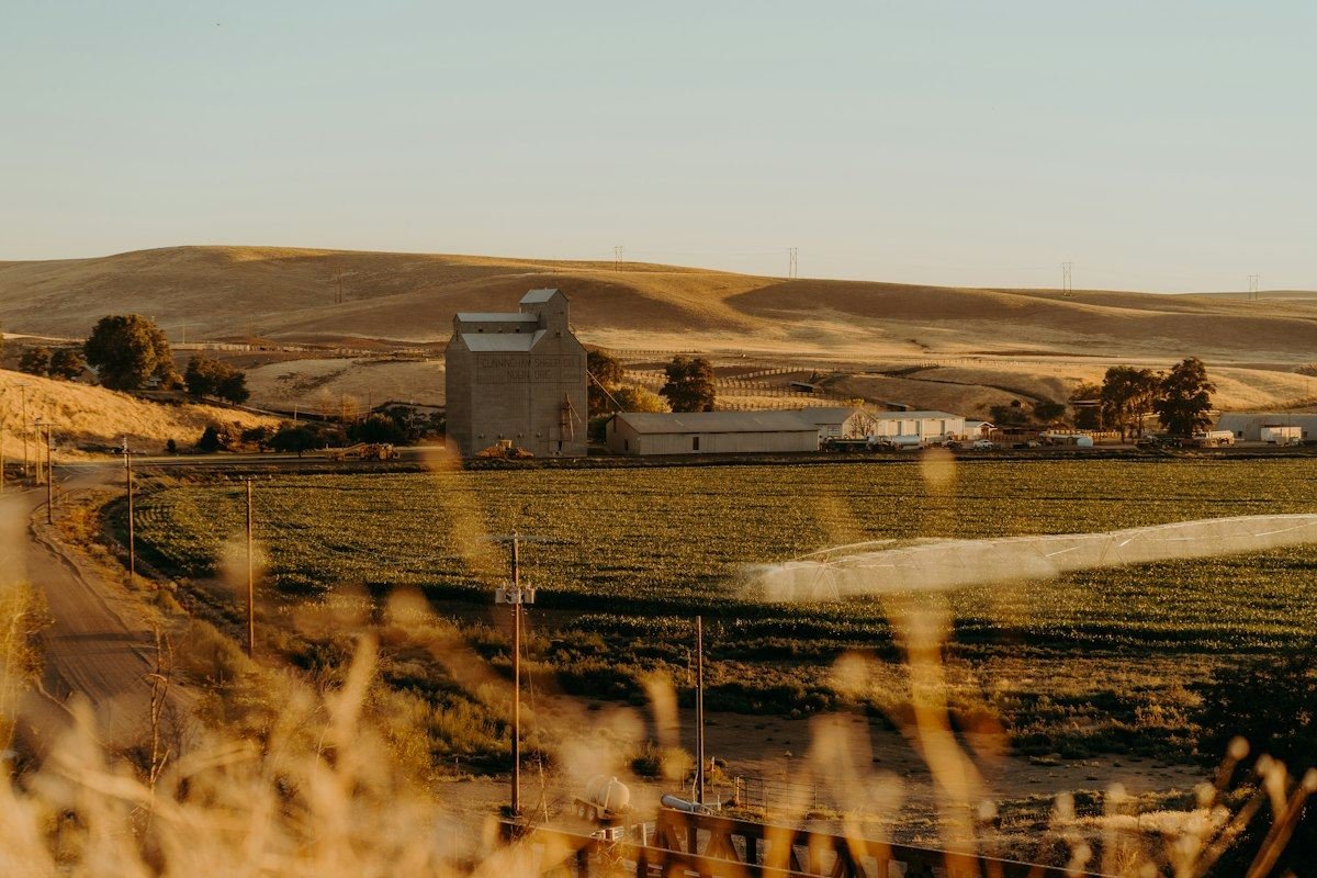 Rural farm with grain silo and fields at sunset