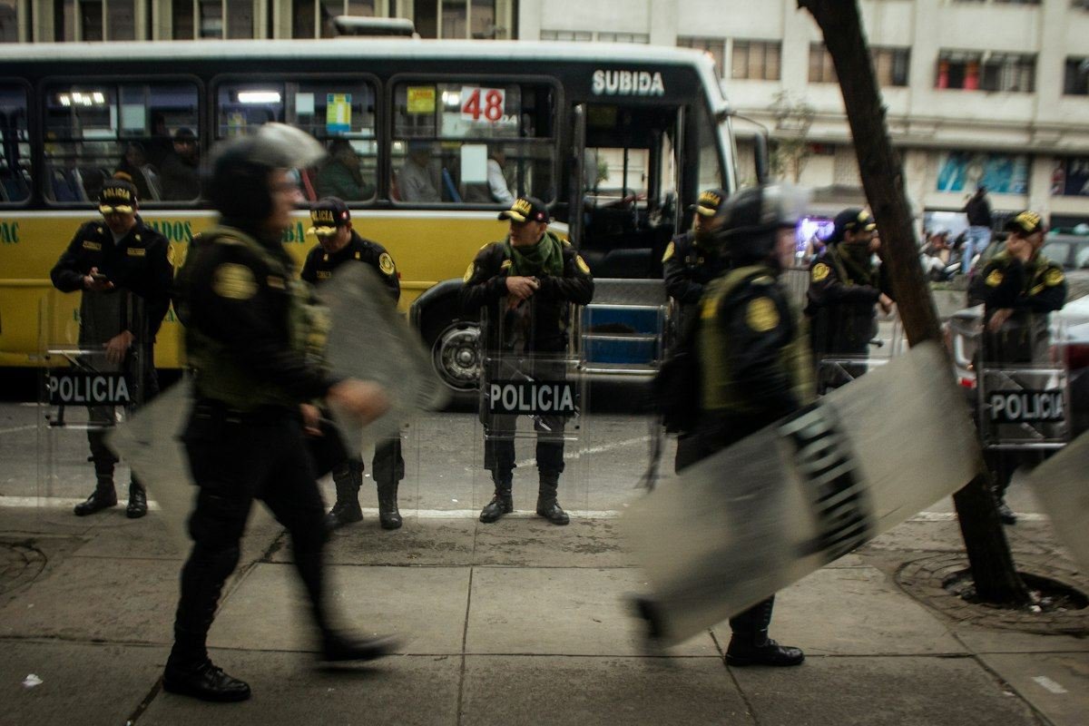 Police officers in riot gear stand on street