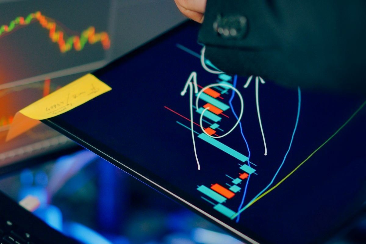 Trader analyzing stock market charts on multiple screens