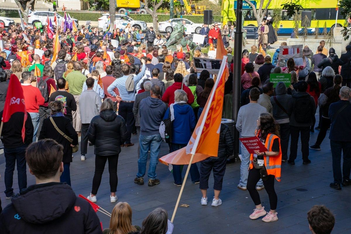 A large crowd of people gathered for a public protest with flags and signs