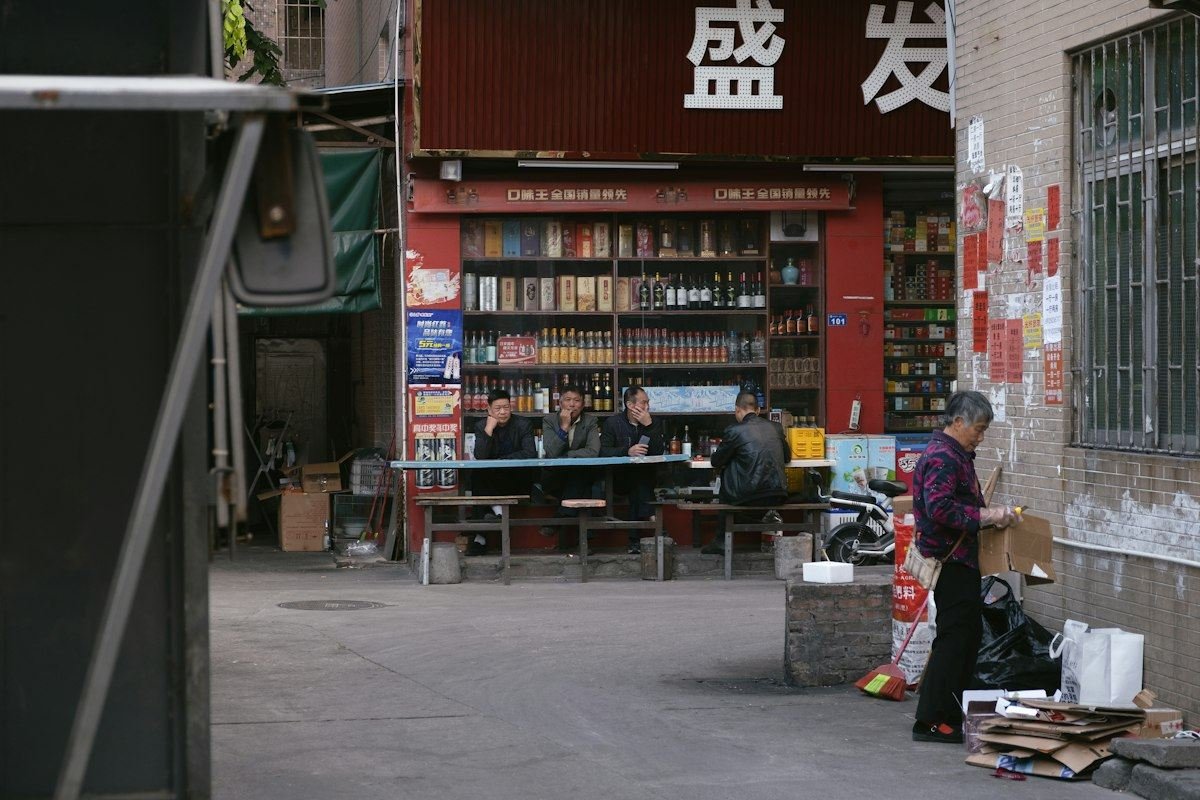People gathered outside a shop with shelves of goods
