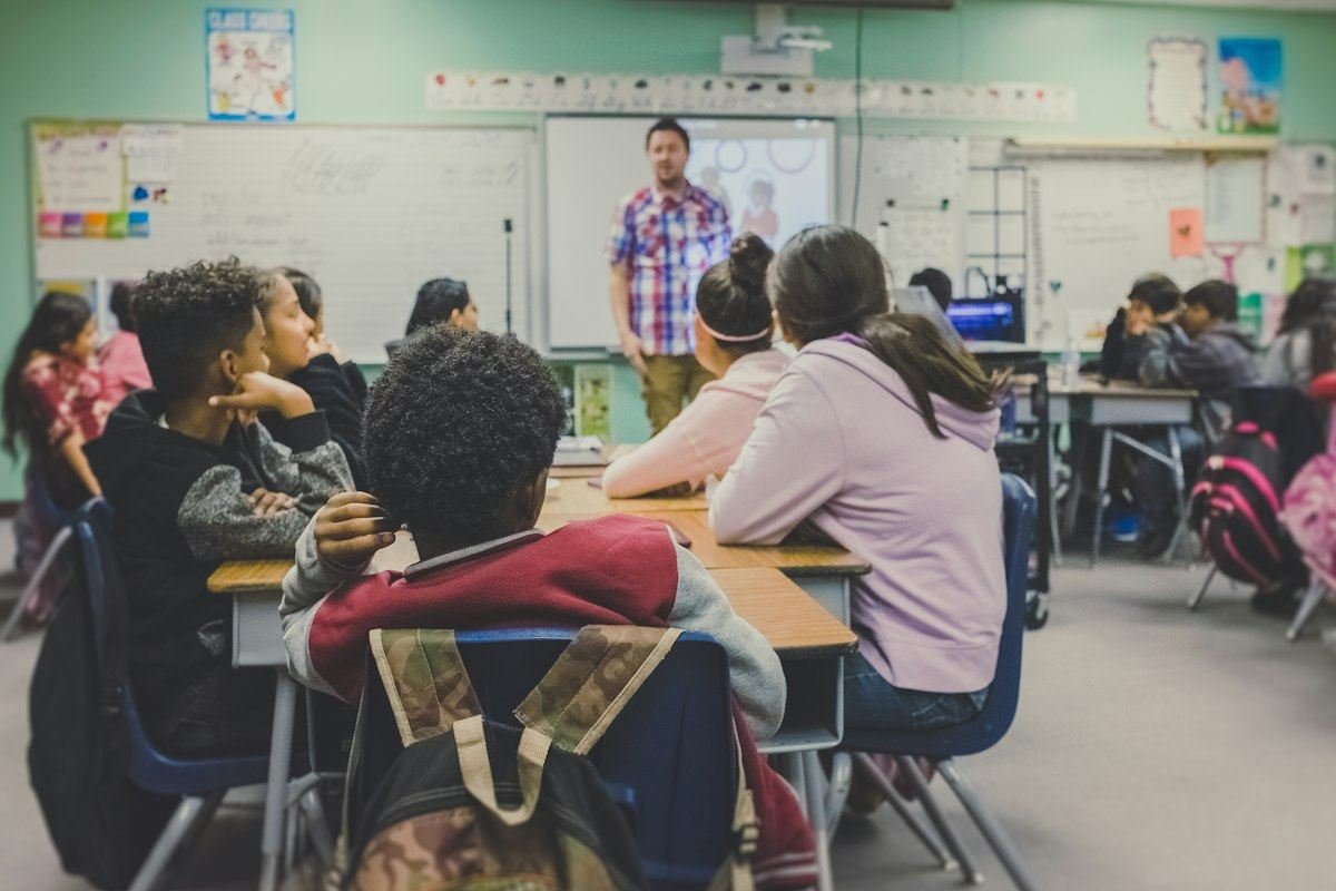 students in classroom with teacher presenting