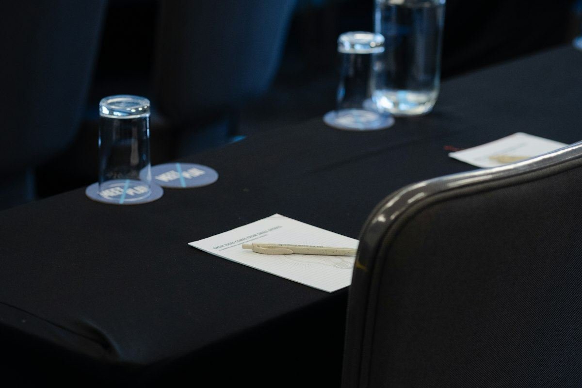 Conference room setup with black tables, chairs, water, and notepads